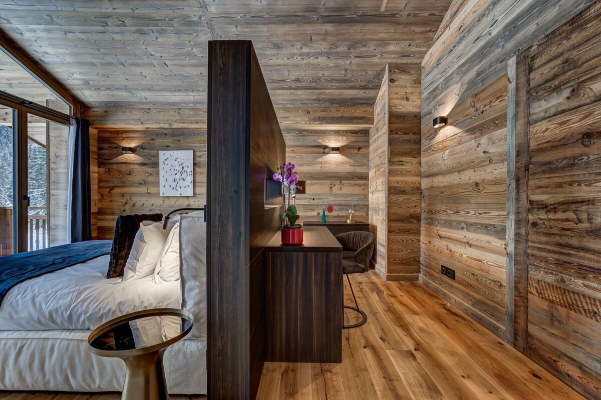 A bedroom with wooden walls and a bed