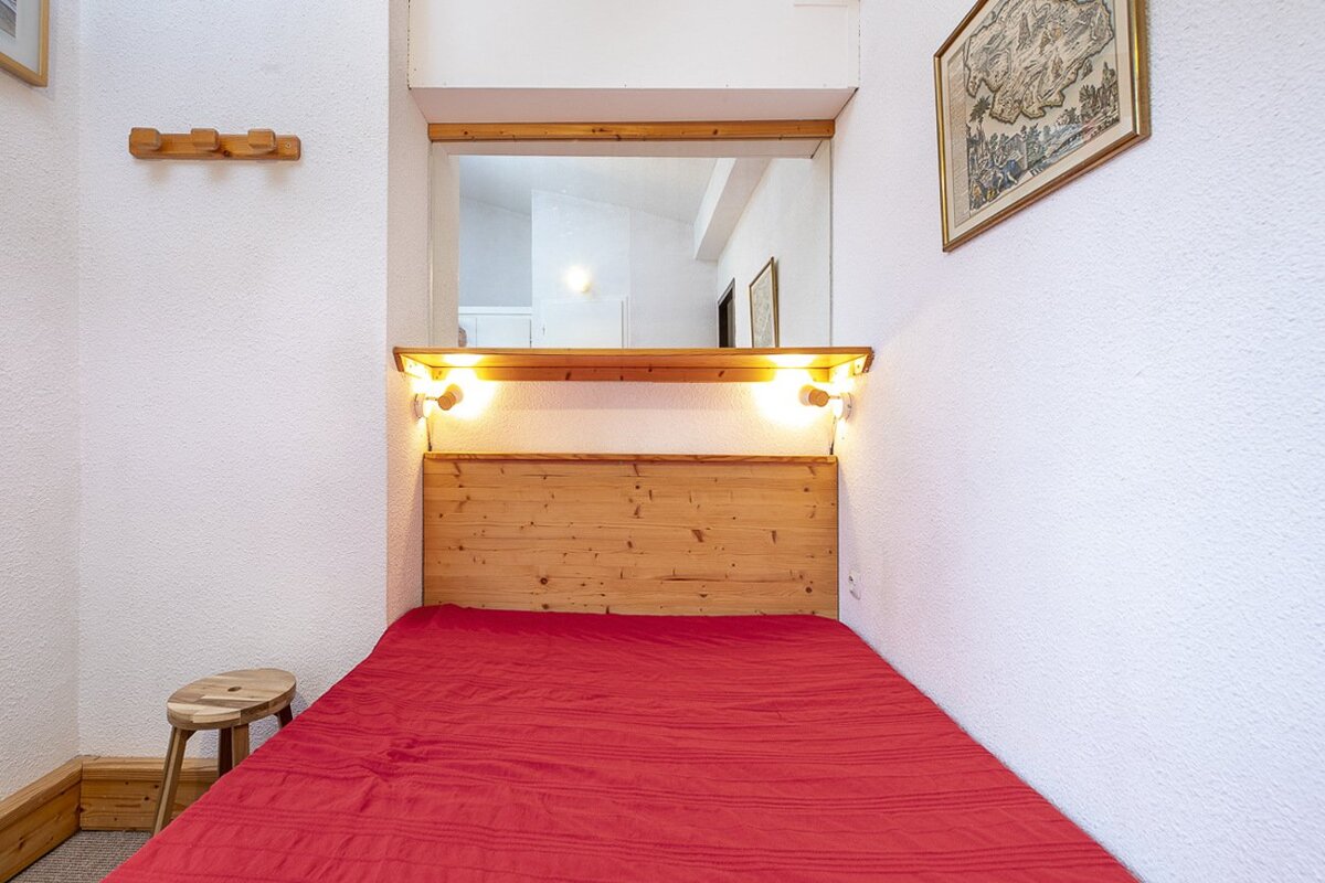 A bedroom with a wooden headboard and a red blanket