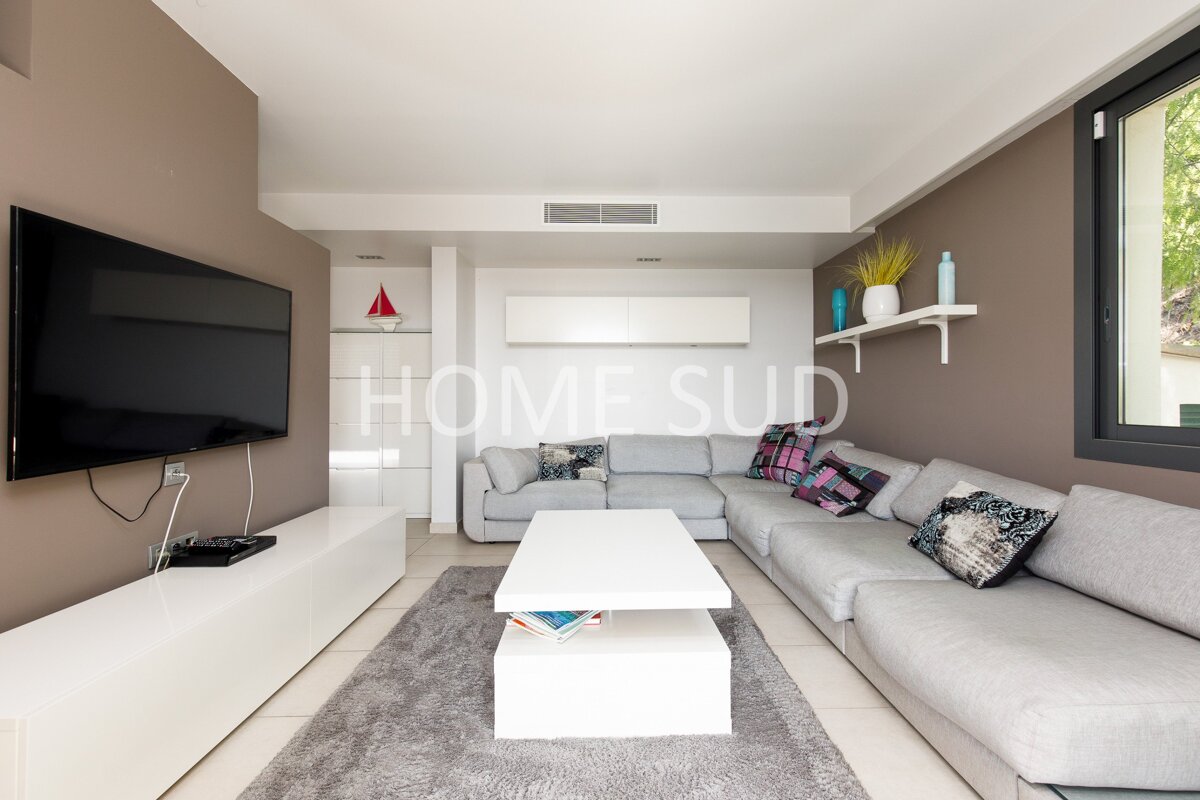 A living room with a large sectional couch and a flat screen tv that says home sud