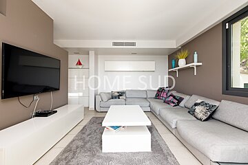 A living room with a large sectional couch and a flat screen tv that says home sud