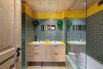 A bathroom with green and yellow tiles and two sinks