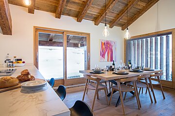A dining room with a table and chairs and a painting on the wall