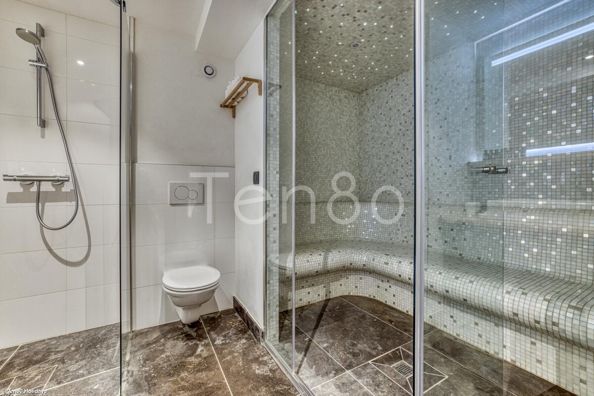 A bathroom with a toilet a shower and a sign that says ten80