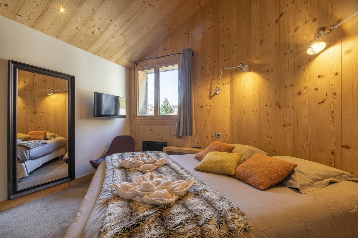 A bedroom with wood paneling and a large bed