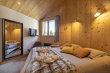 A bedroom with wood paneling and a large bed