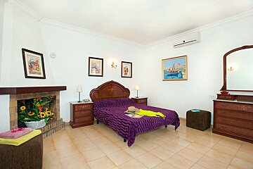 A bedroom with a purple bed and a fireplace