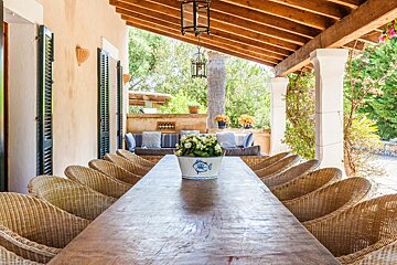 A long table with wicker chairs and a vase of flowers on it
