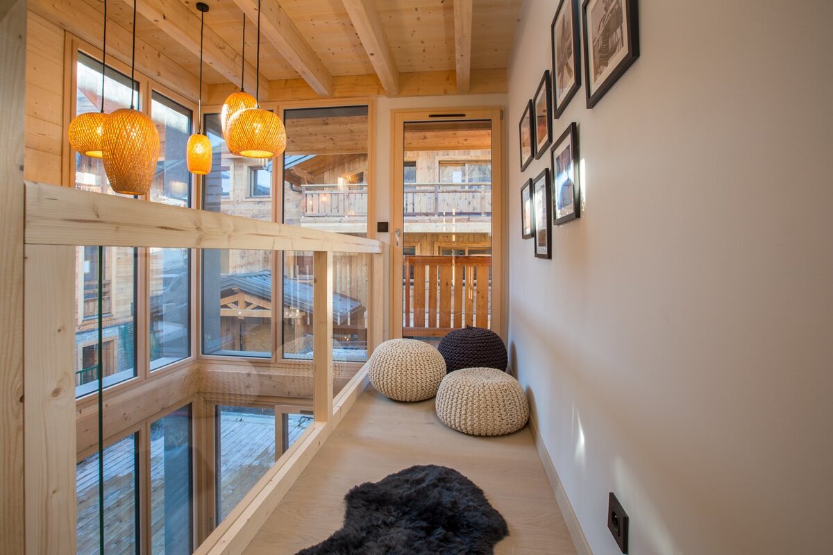 A hallway with a lot of windows and ottomans