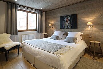 A bedroom with a painting on the wall above the bed