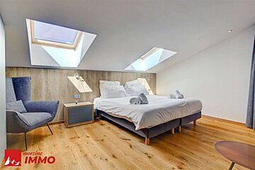 A bedroom with a bed and a chair and a sign that says morzine immo