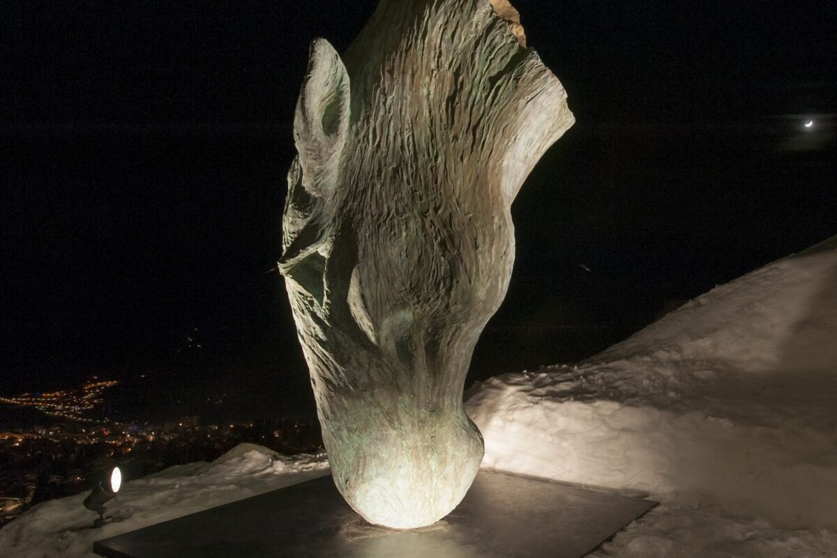 A large sculpture is lit up at night in the snow