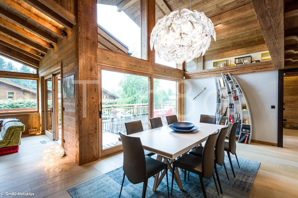 A dining room with a table and chairs and a chandelier