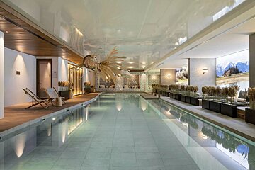 Luxurious indoor pool with modern design, lounge areas, natural decor, and mountain wall art, creating a tranquil spa ambiance.