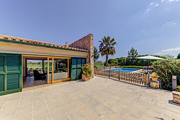 A patio with a fence and a pool in the background