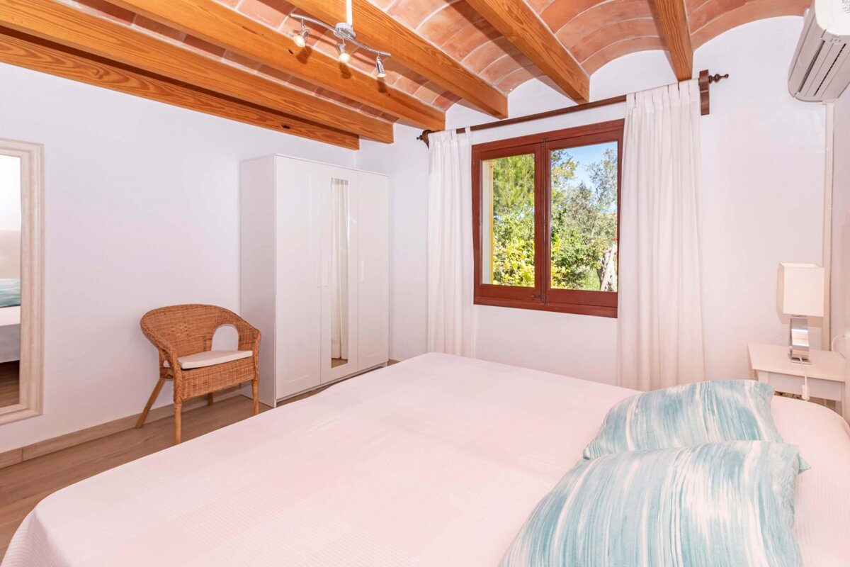 A bedroom with a bed a chair and a window