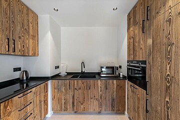 A kitchen with wooden cabinets and black counter tops
