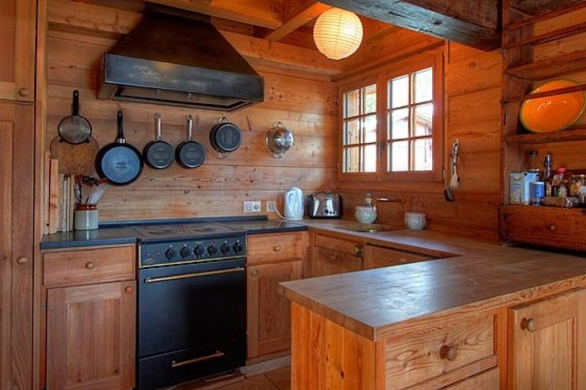 A kitchen in a log cabin with wooden cabinets and a black stove