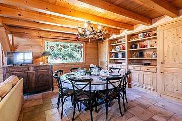A dining room with a table and chairs and a television