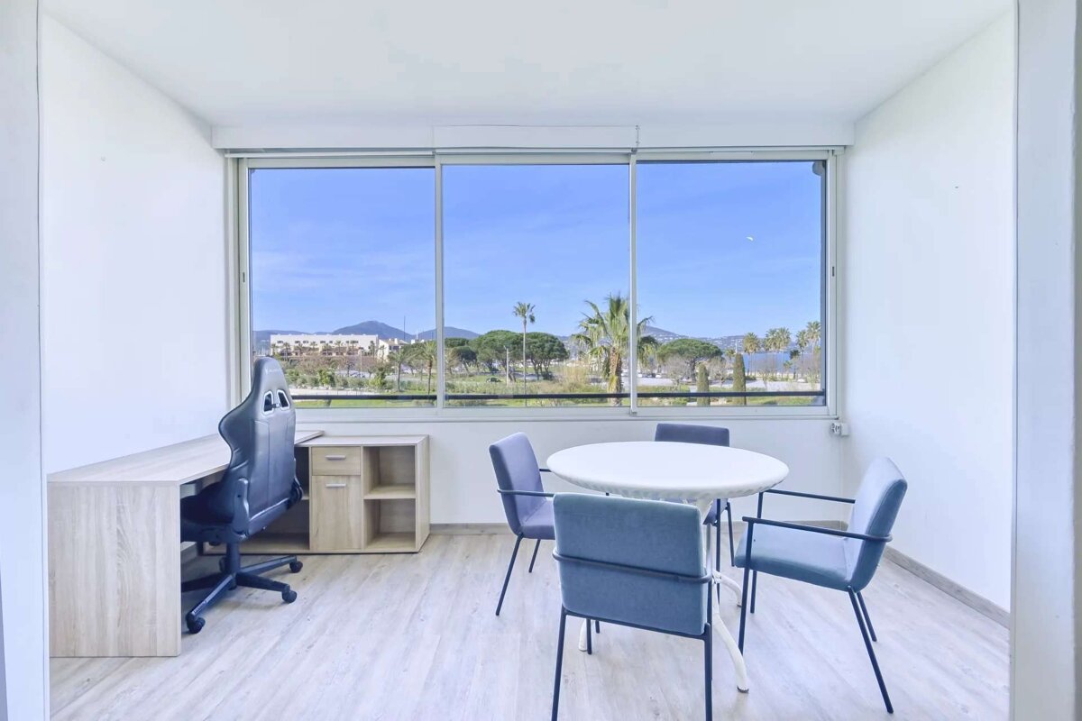 A room with a table and chairs and a large window
