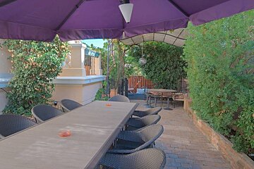 A patio with a table and chairs under a purple umbrella