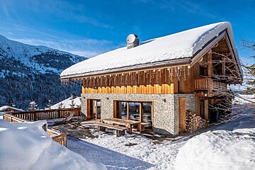 A snowy house with a table and chairs outside