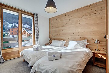 A bedroom with two beds and a wooden wall