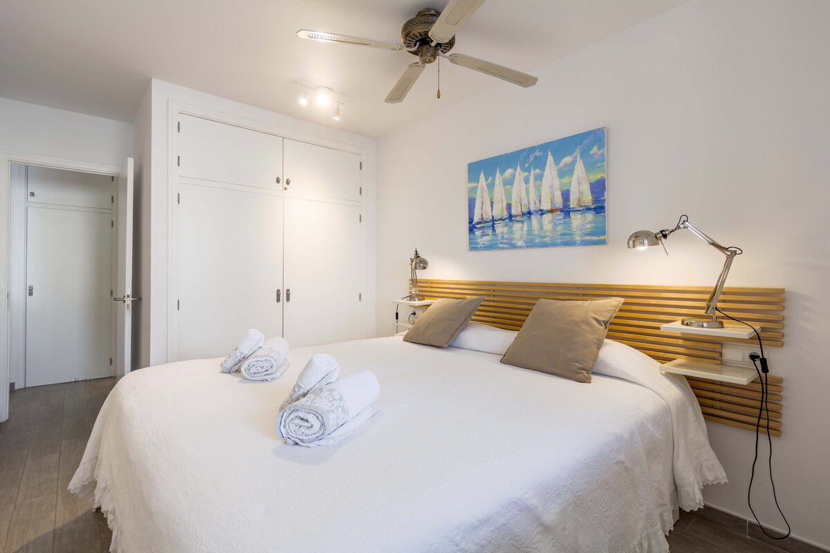 A bedroom with a painting of sailboats above the bed