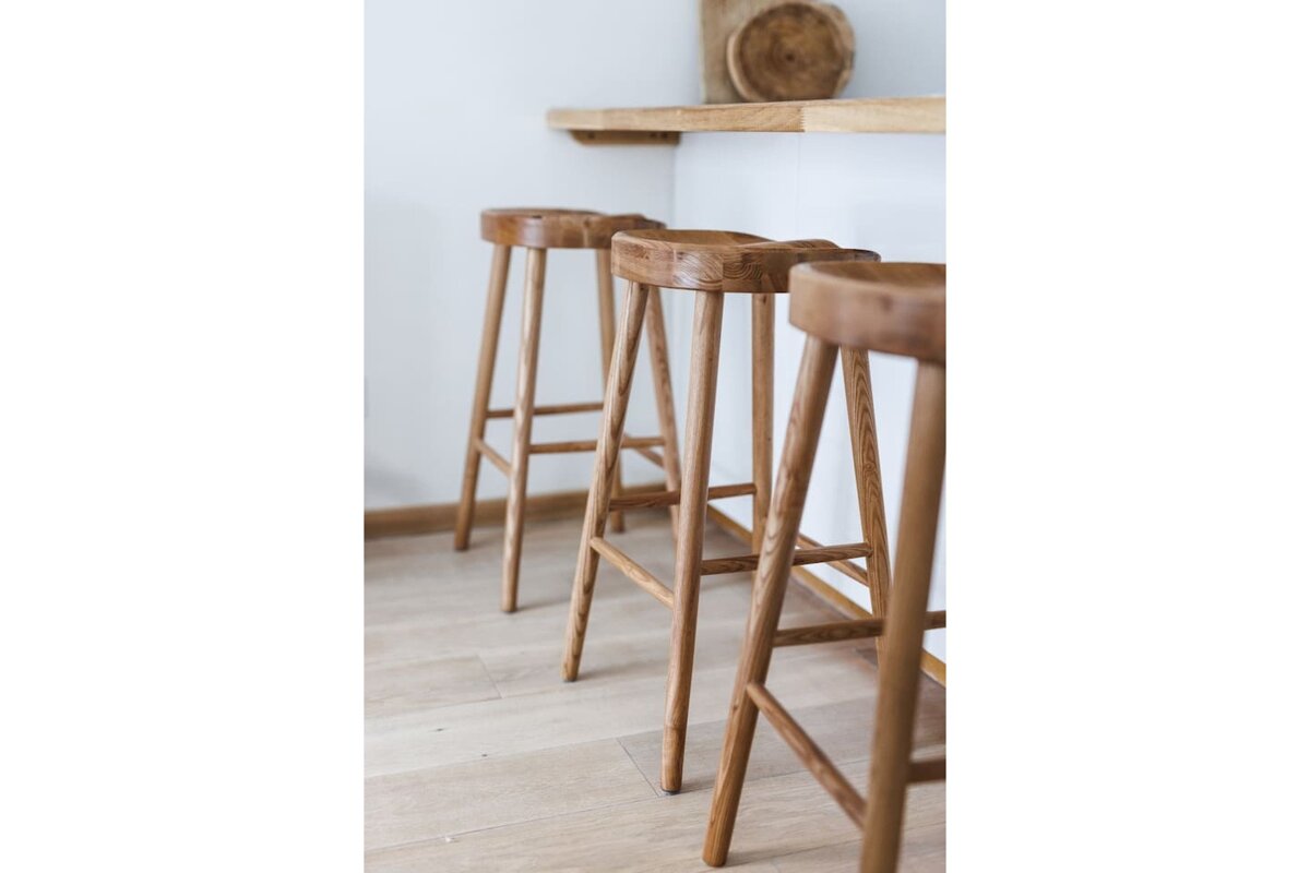 Three wooden bar stools are lined up next to each other