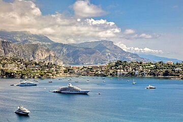 A few boats in the water with mountains in the background