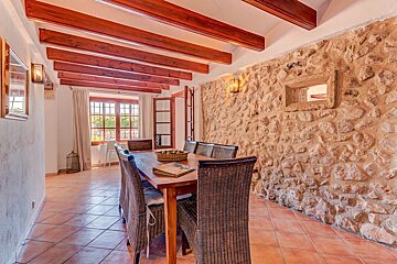 A dining room with a stone wall and wooden beams