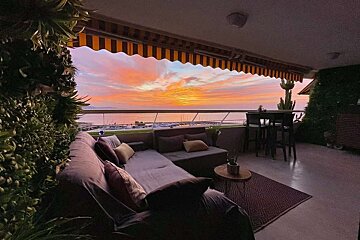 A balcony with a view of the ocean at sunset