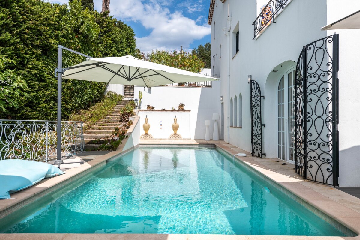 A large swimming pool with a white umbrella in front of it