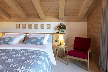 A bedroom with a bed and a red chair