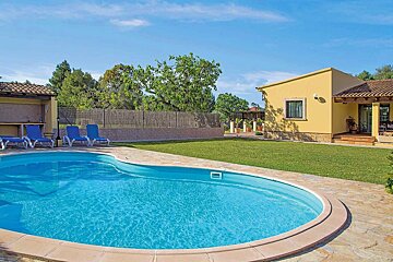 A yellow house with a large swimming pool in front of it