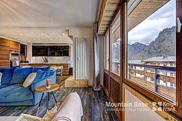 A living room with a blue couch and the words mountain base on the wall