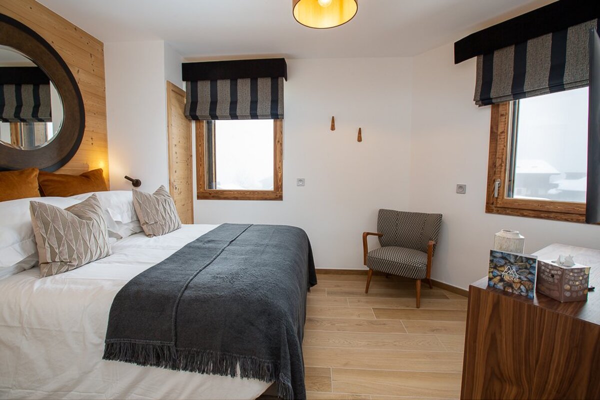 A bedroom with a bed a chair and a mirror