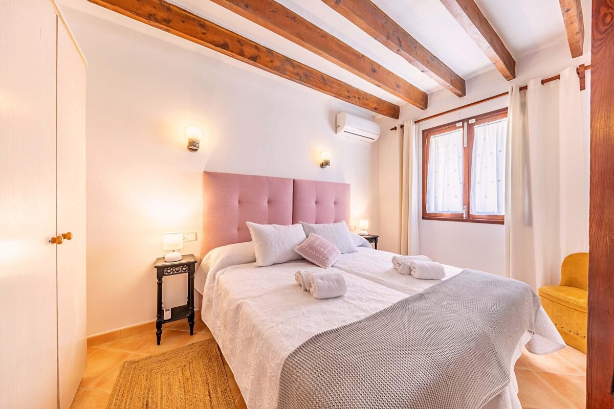 A bedroom with a pink headboard and white sheets