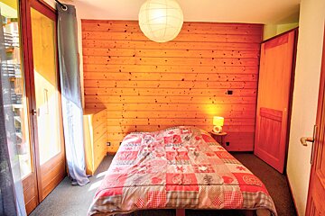 A bedroom with a bed and a wooden wall