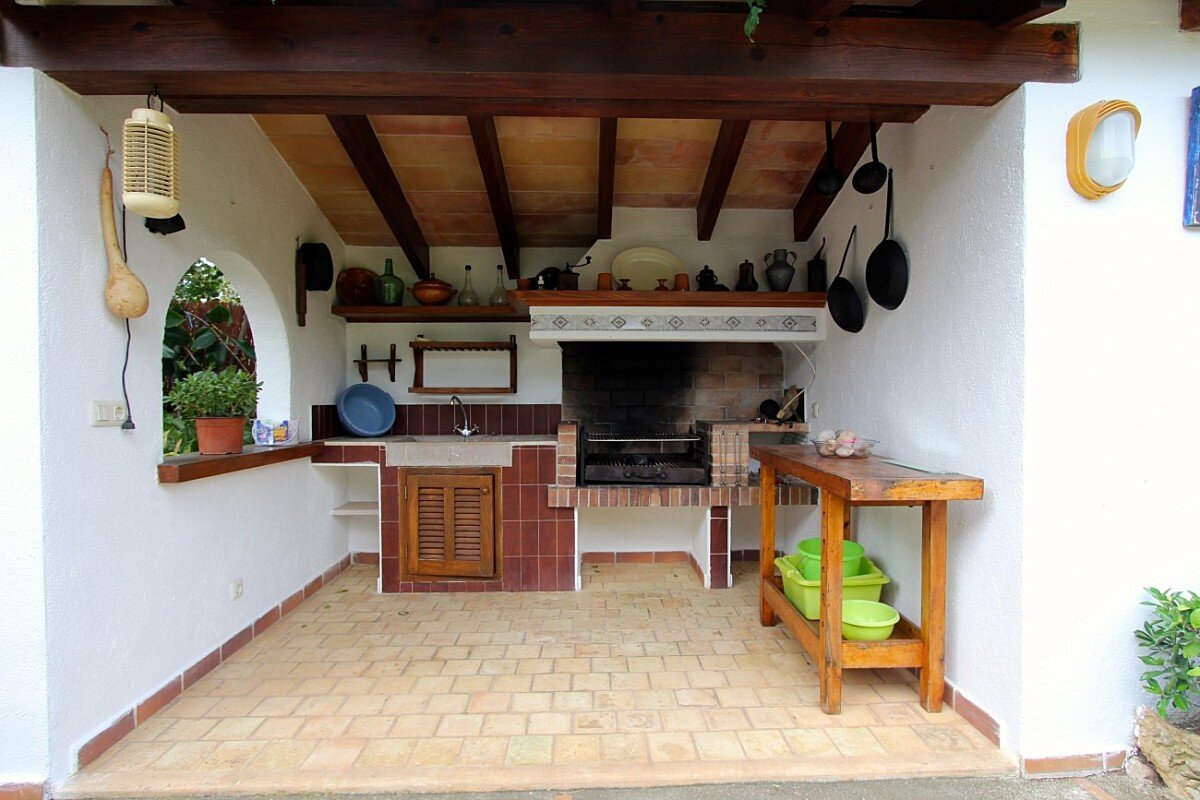 A kitchen with a stove and a shelf with pots and pans on it