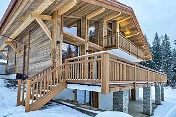 A wooden house with stairs leading up to the second floor