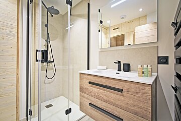 A bathroom with a walk in shower and a sink