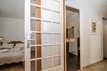 A glass door leads to a bathroom and a bedroom