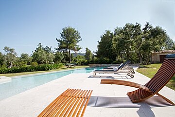 A swimming pool surrounded by chairs and trees on a sunny day