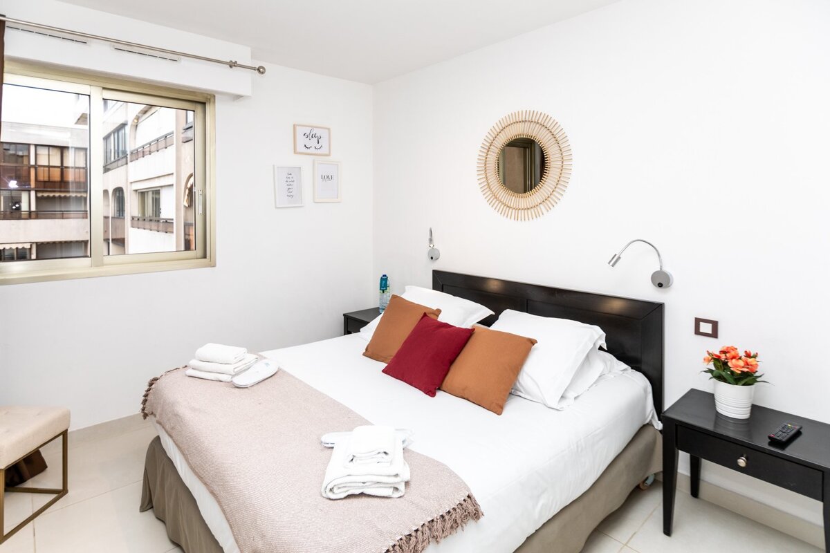 A bedroom with a bed a nightstand and a mirror