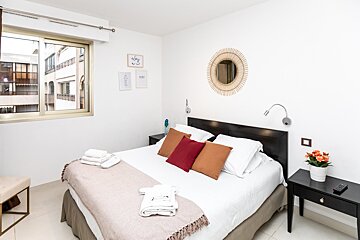 A bedroom with a bed a nightstand and a mirror