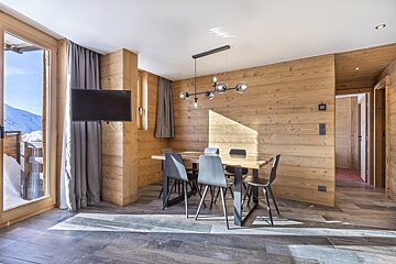 A dining room with a table and chairs and a flat screen tv