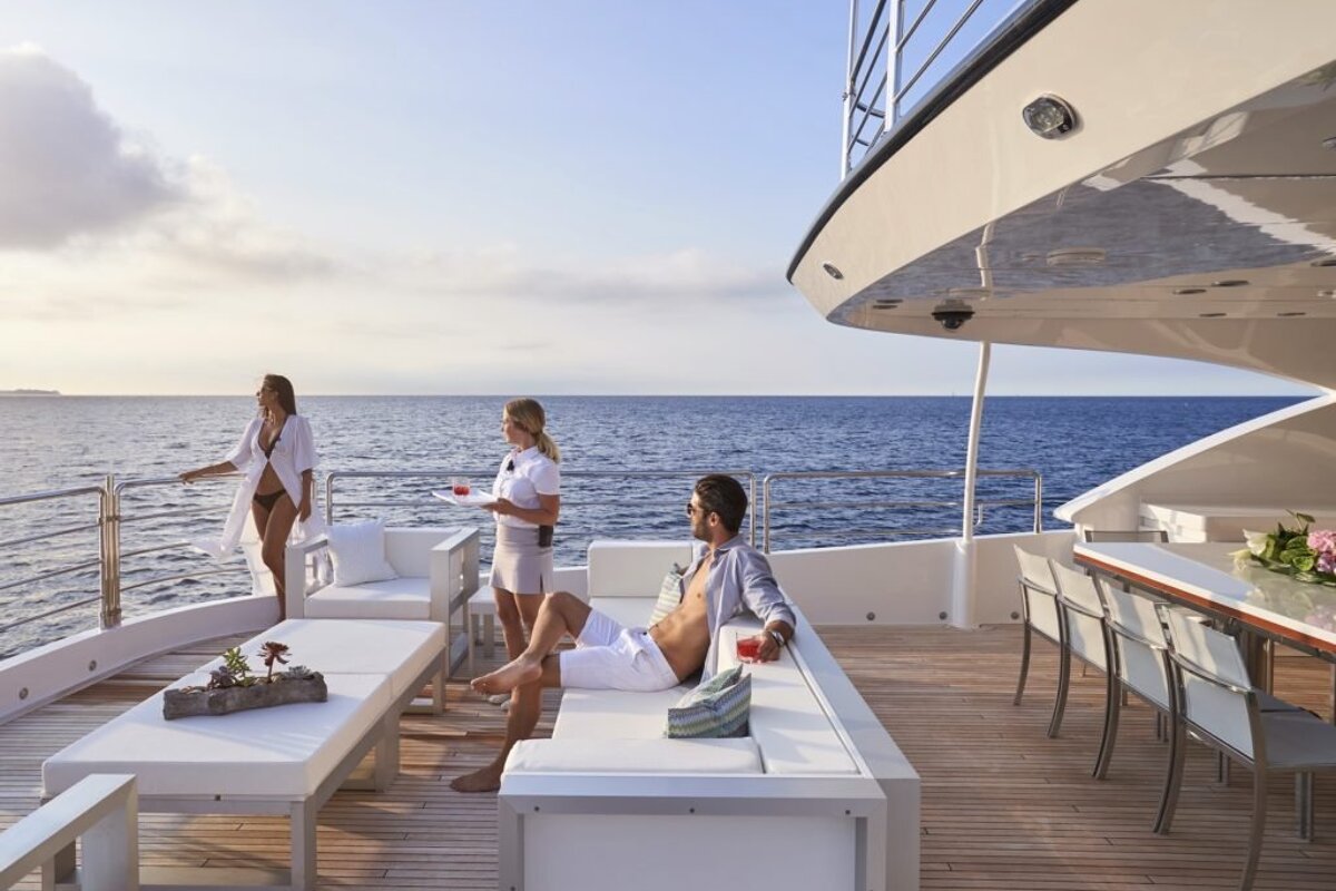 A man sits on a couch on the deck of a boat