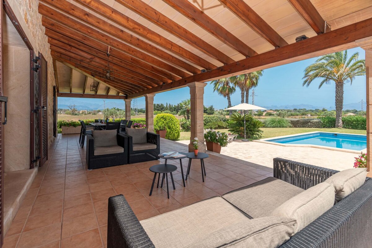 A patio with a couch and chairs under a wooden roof