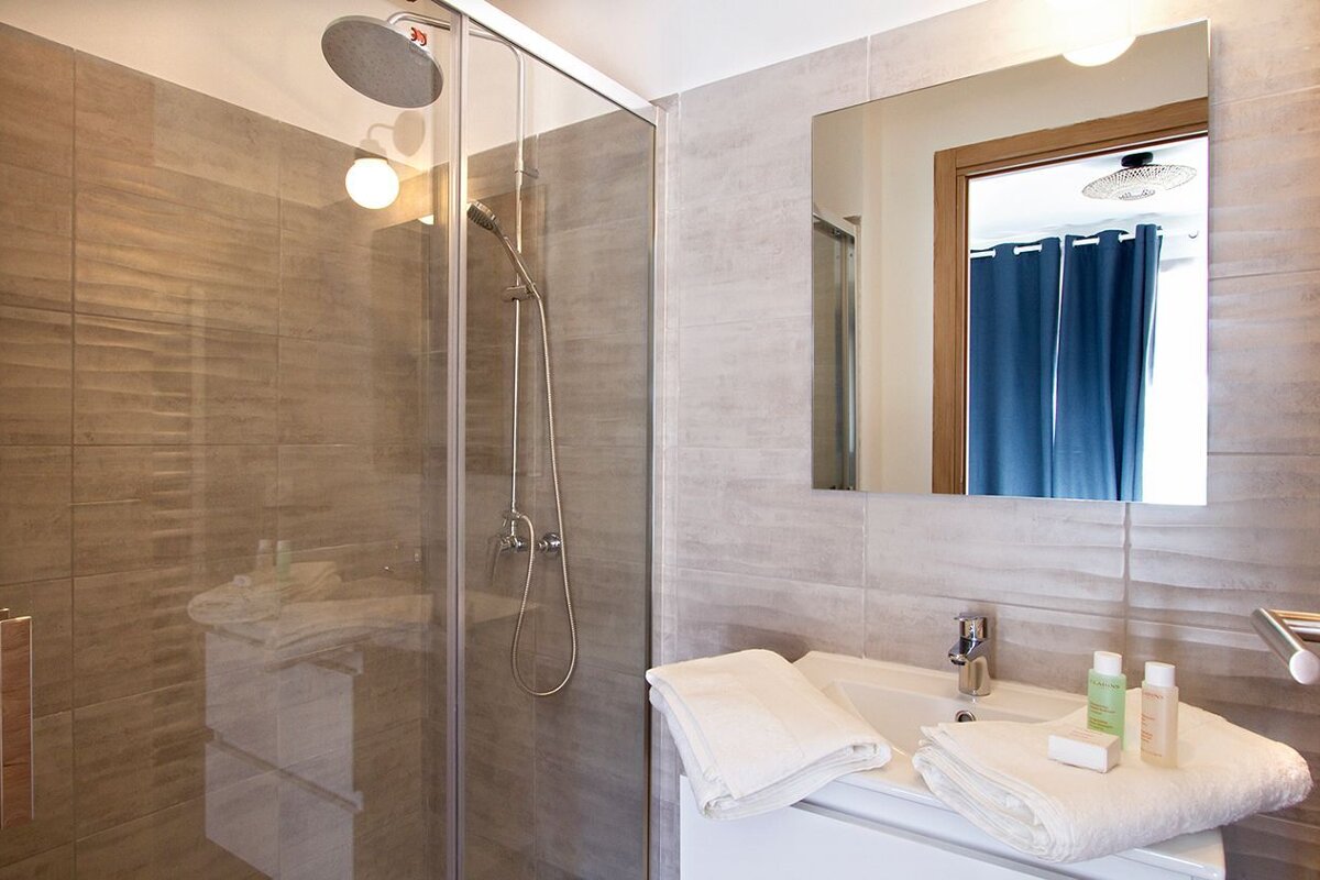 A bathroom with a sliding glass shower door and a sink