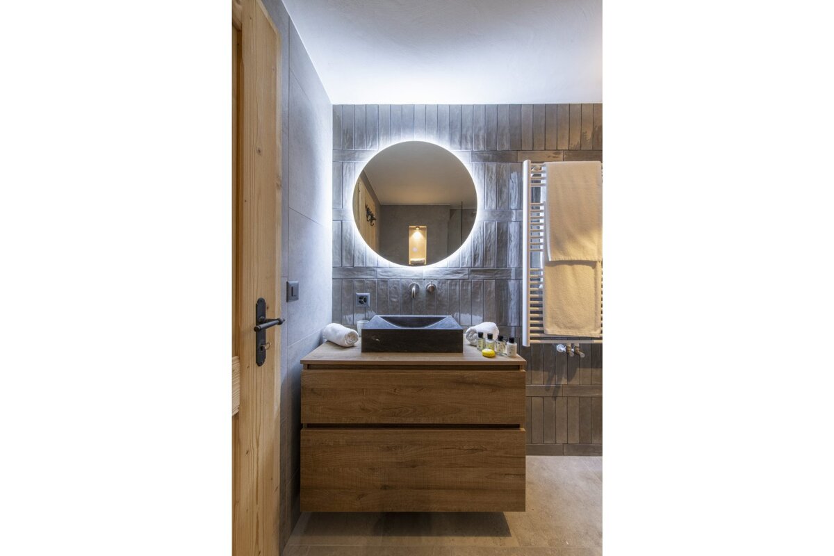 A bathroom with a sink and a round mirror